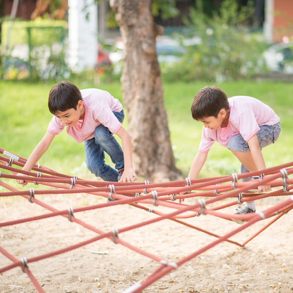 Two children climbing on playground netting